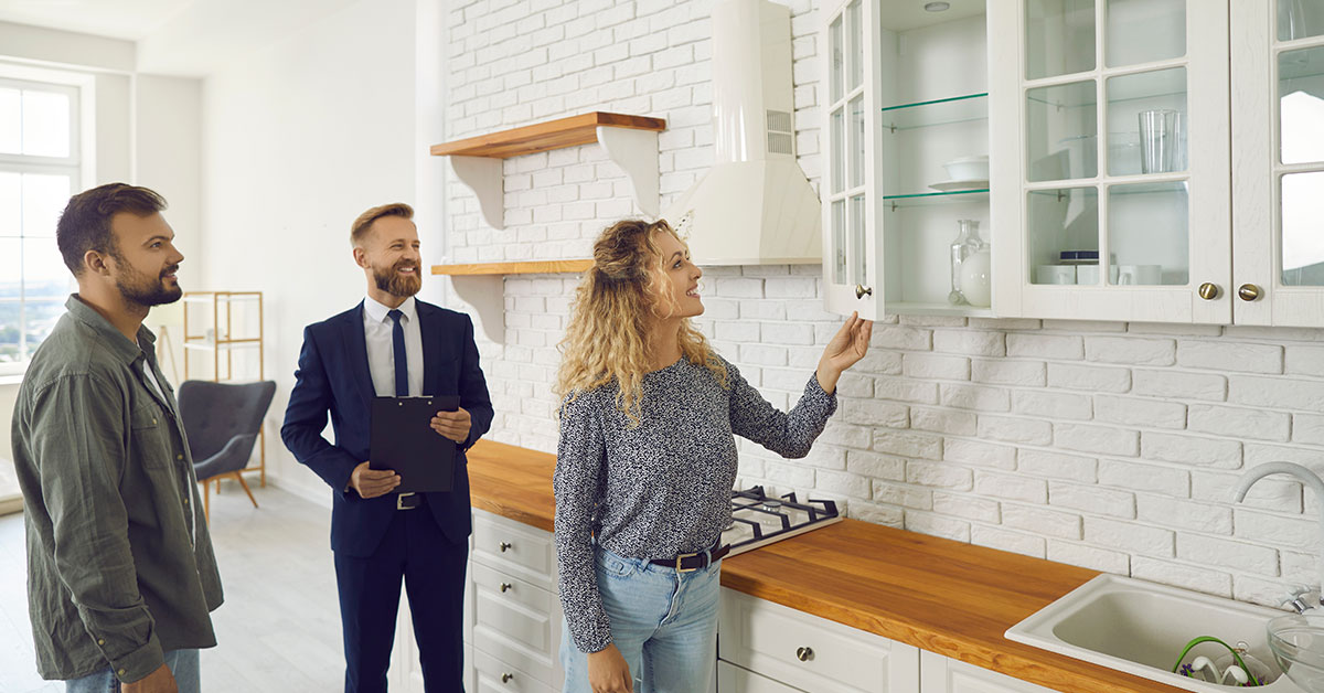 Couple inspects the kitchen during an open house tour with their realtor.
