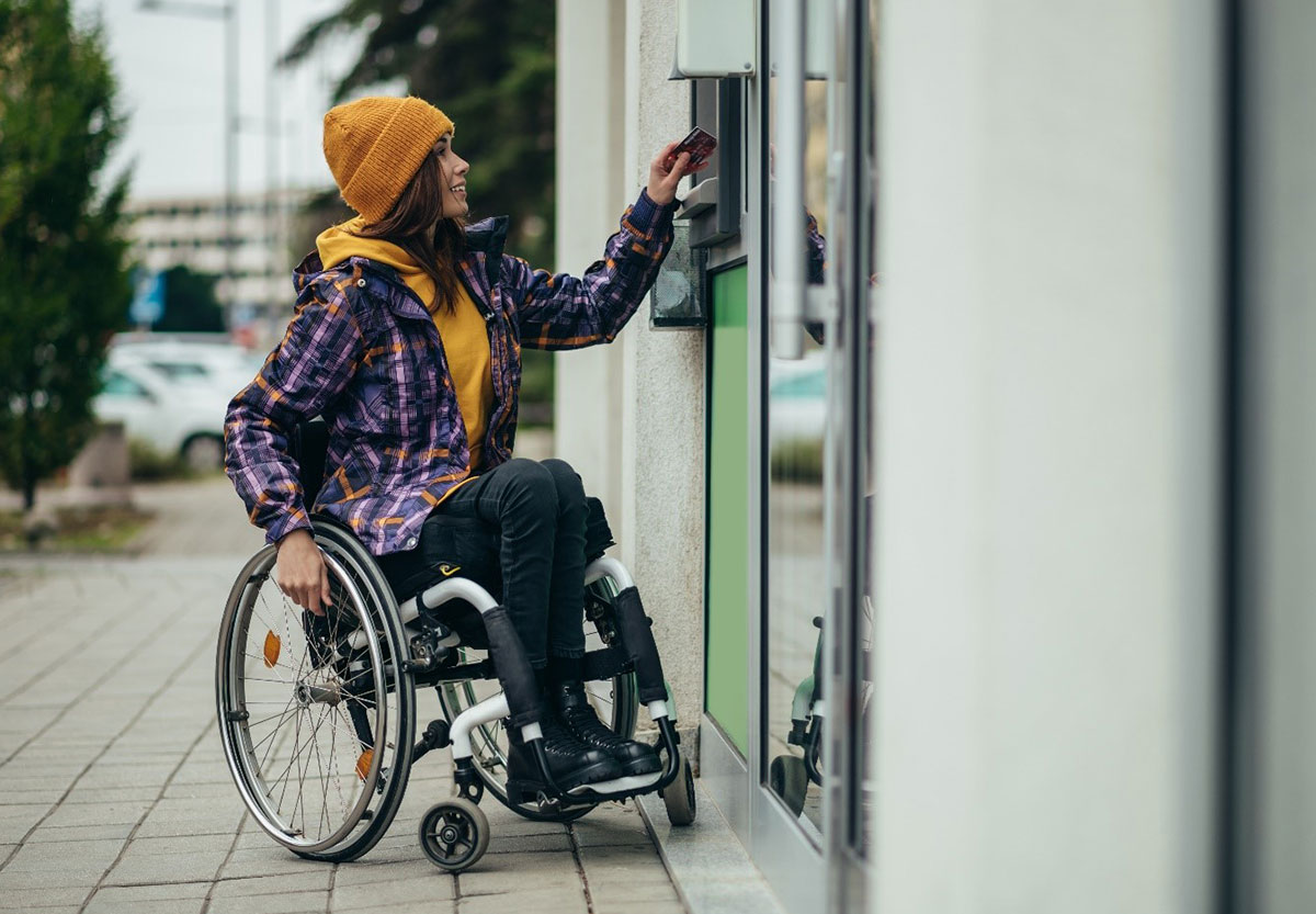 Woman in a wheelchair uses her debit card at an ATM.