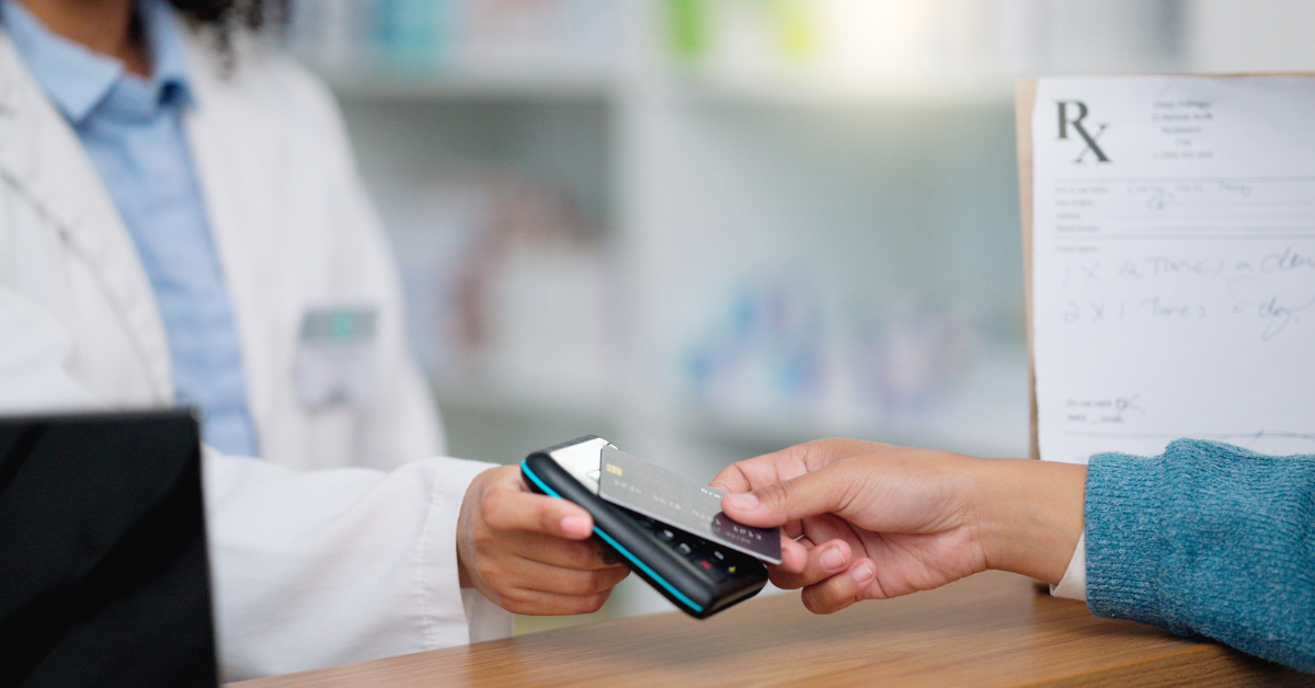 A person taps their credit card on the POS device at the pharmacy.