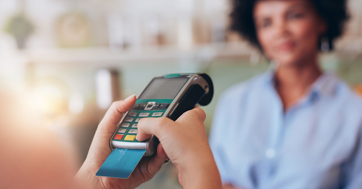 Woman enters her pin into the credit card reader as she pays for her items