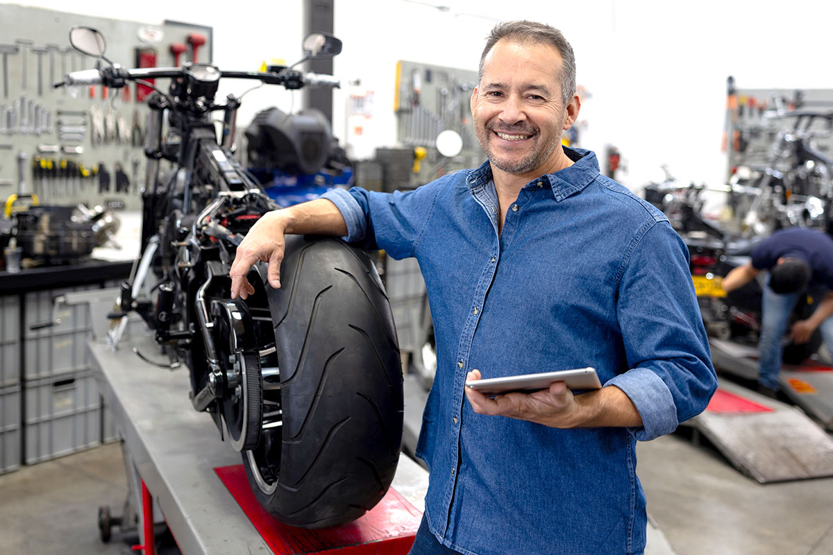 Man Next to Motorcycle with Tablet in Hand