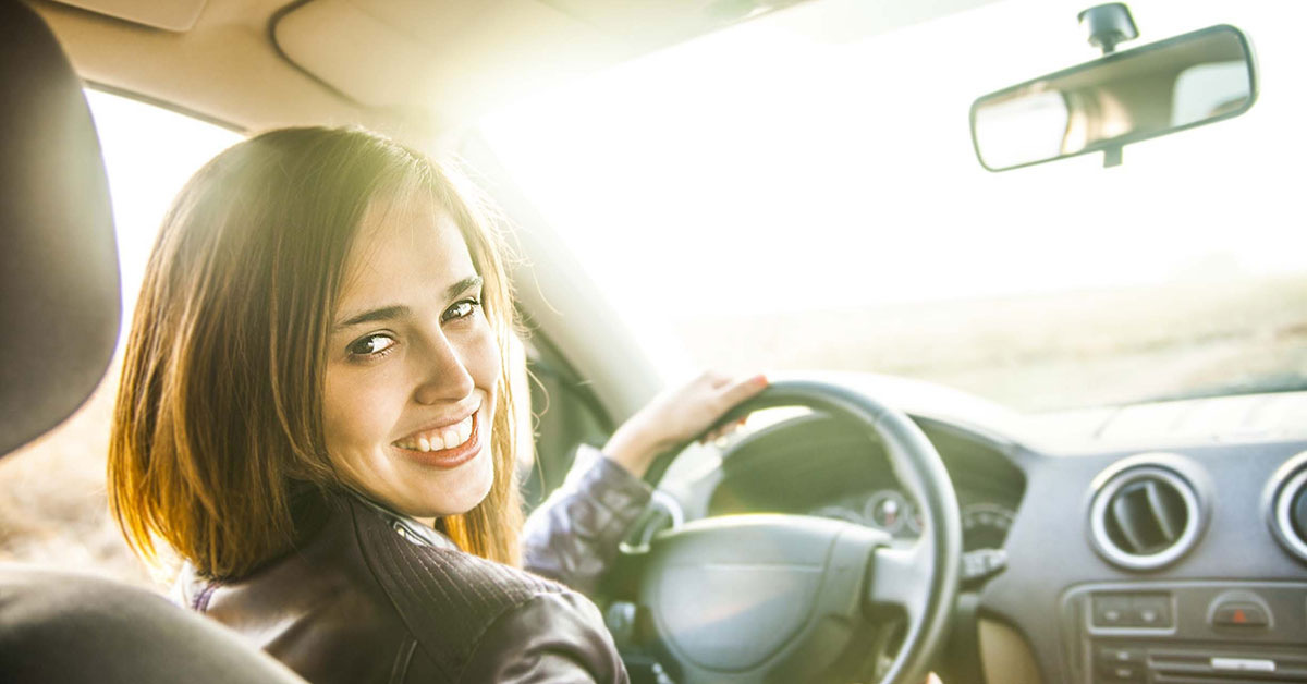 woman sitting the front seat of a car looking back.