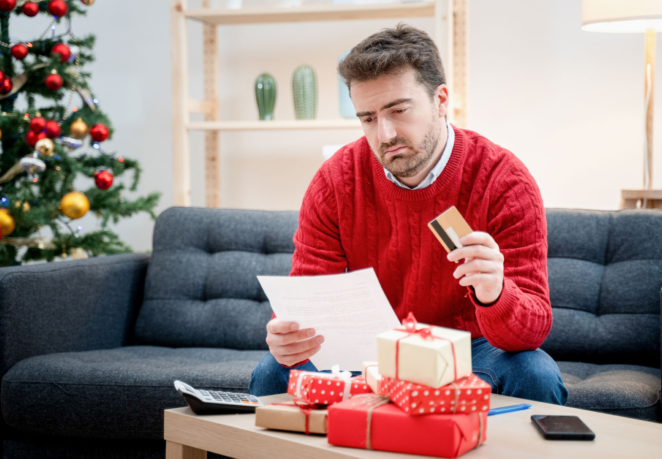 a man looking dejected at a billing notice while holding a credit card.