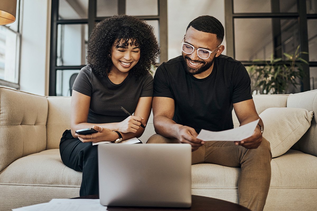 couple sitting on a couch looking at a laptop