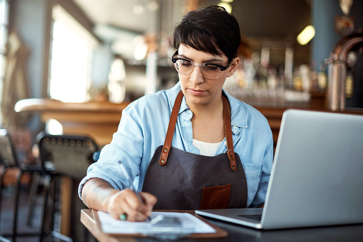 Woman Writing Next to Laptop