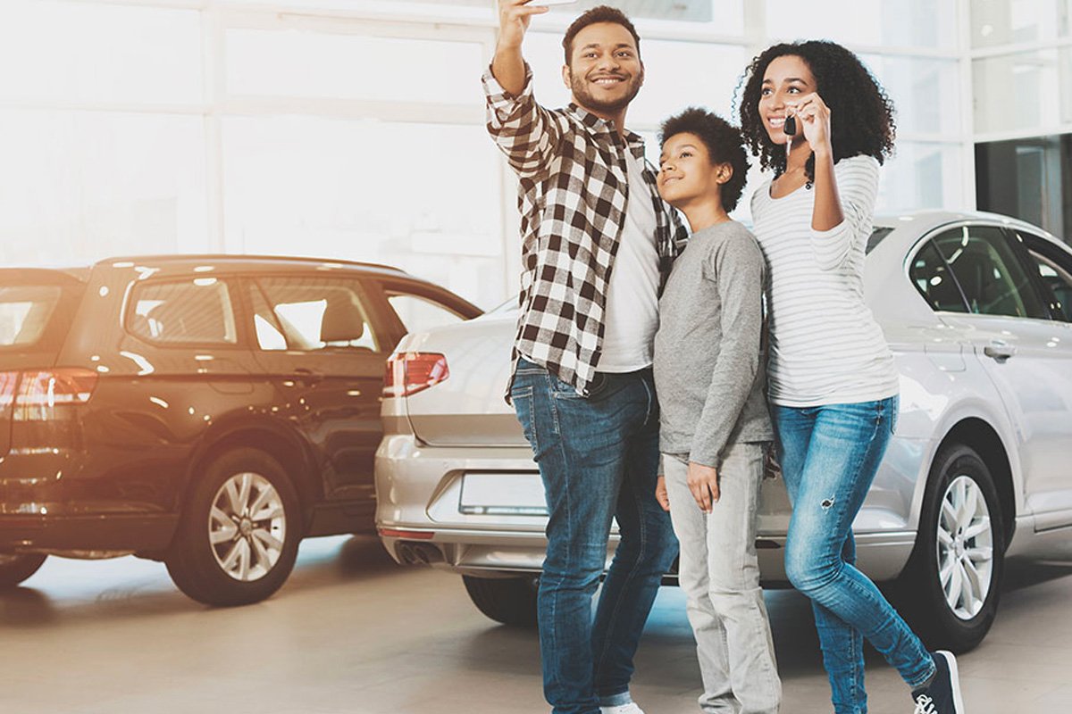 A family taking a selfie while showing off the keys to their new car.