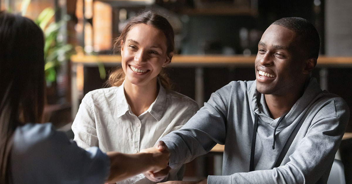 Couple shakes hands with a financial representative after signing off on their personal loan