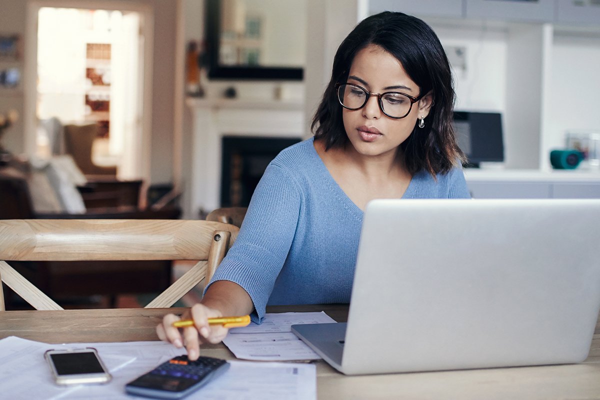 woman in front of her laptop while using a calculator