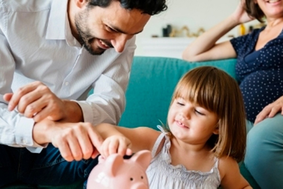 adult and child placing money into a pink piggy bank