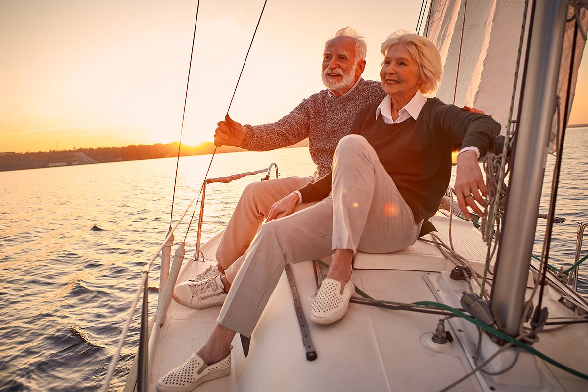A mature couple on sailboat smiling in the early evening.