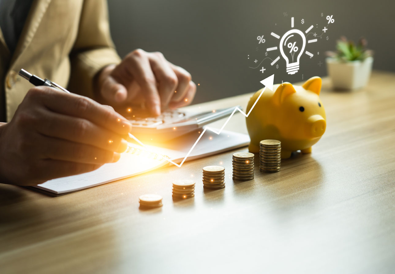 person calculating their savings in front of a piggy bank and coins.