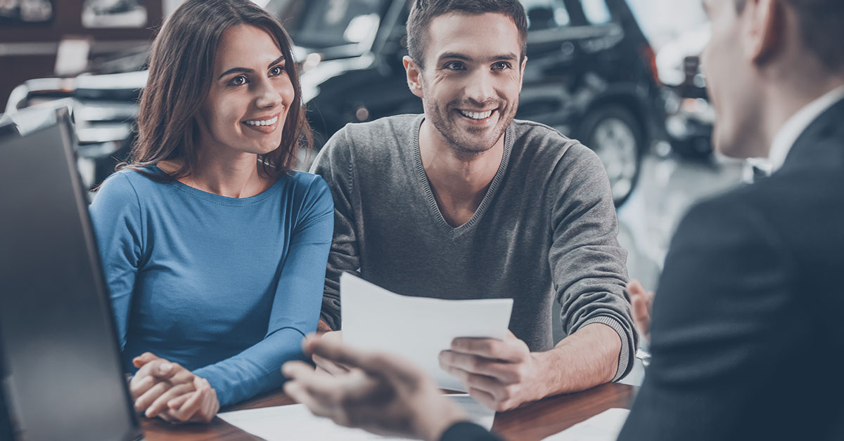 Happy couple at a car dealership reviewing finance options
